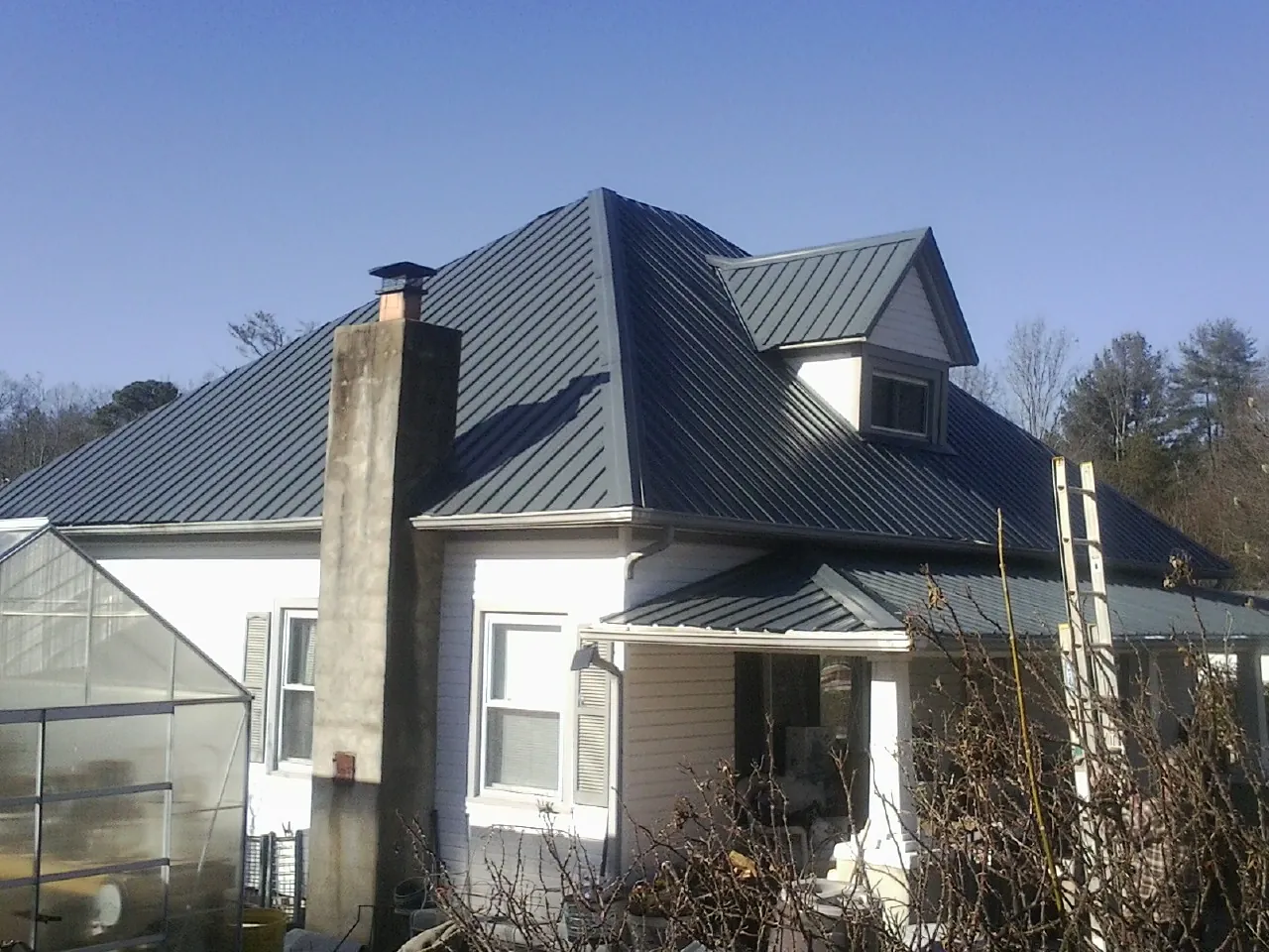 Dark blue standing seam metal roof on a white farmhouse with dormer — Slate & Tile Roof Repair by Roofing Brothers in Rosburg