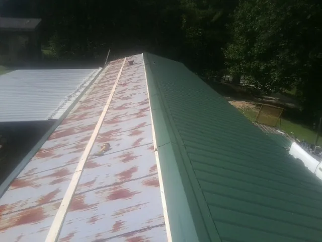 Old rusted panels beside newly installed green metal roofing — Wind Damage Roof Repair by Roofing Brothers in Rosburg