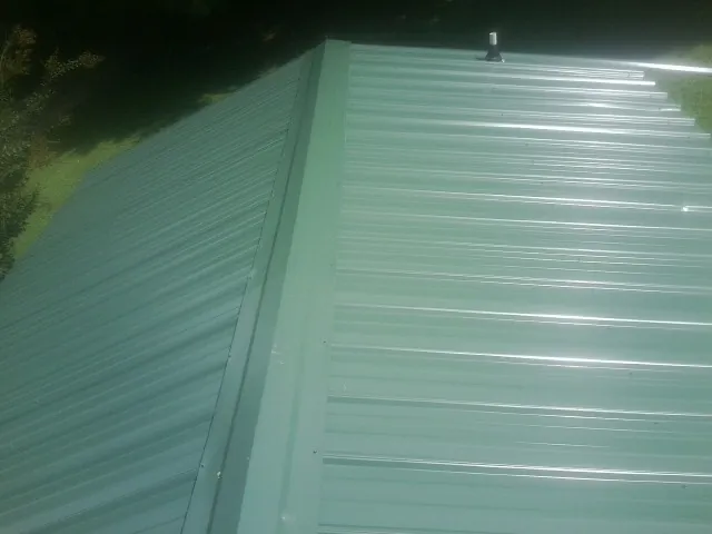 New green metal panels meeting at the ridge of a roof — Flat Roof Repair work by our crew in Rosburg