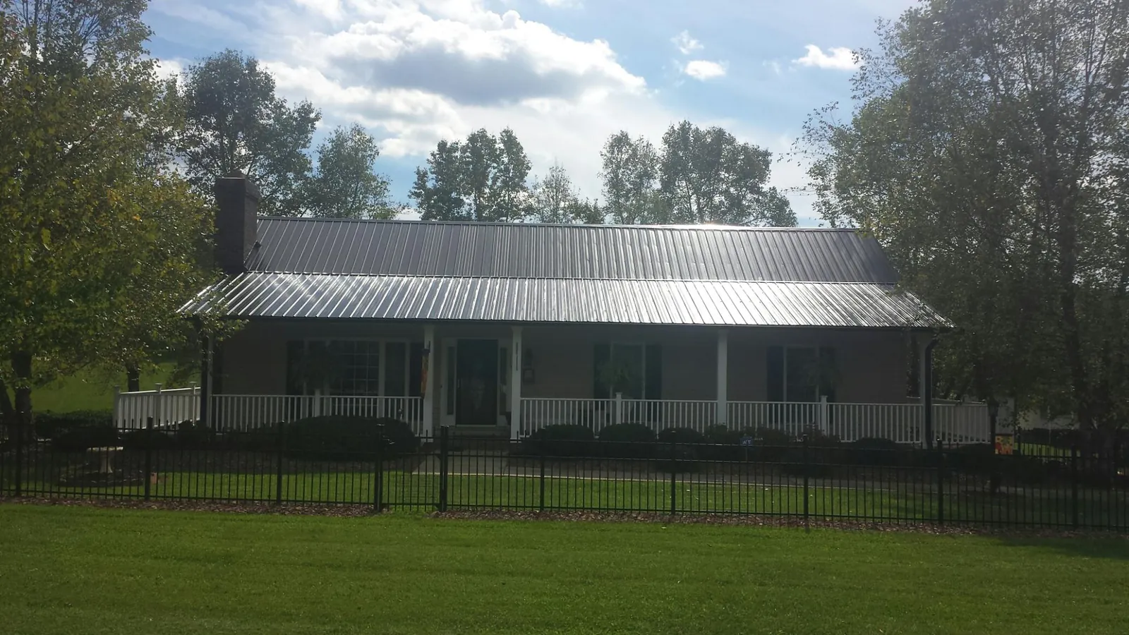 Gray metal roof on a brick ranch with a full width front porch — Gutter Guard Installation work by our crew in Rosburg