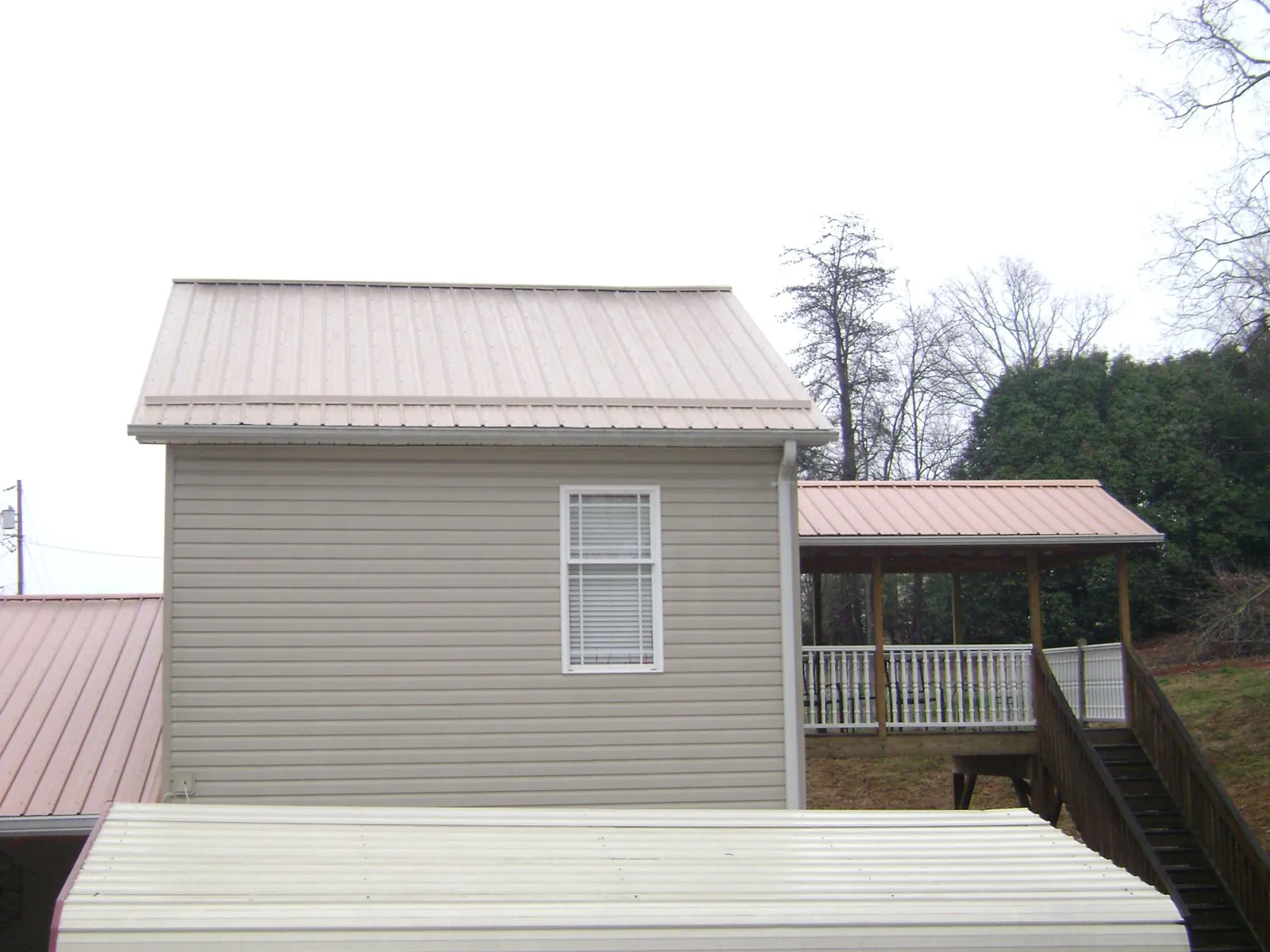 Tan metal roofs on a two story addition and attached porch, from a Roof Replacement job in Rosburg