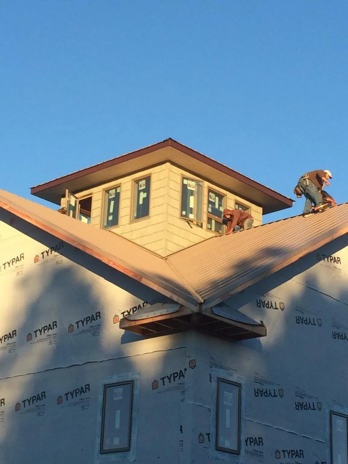 Roofers working around a rooftop cupola on a new metal roof at sunset — Roof Waterproofing in Rosburg by Roofing Brothers